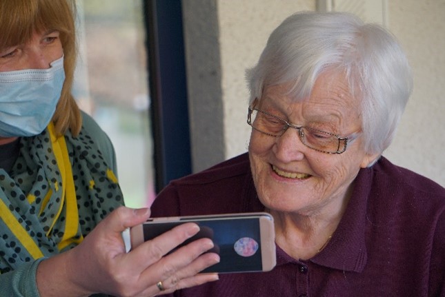Elderly lady looking at mobile phone with staff