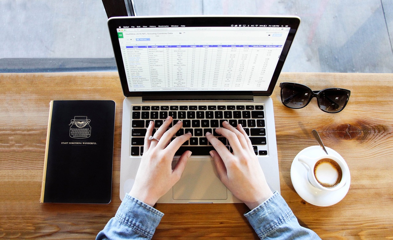 Person on a laptop, notebook and a cup of coffee